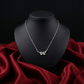 Silver necklace with leaf design on a black mannequin bust against a red fabric background