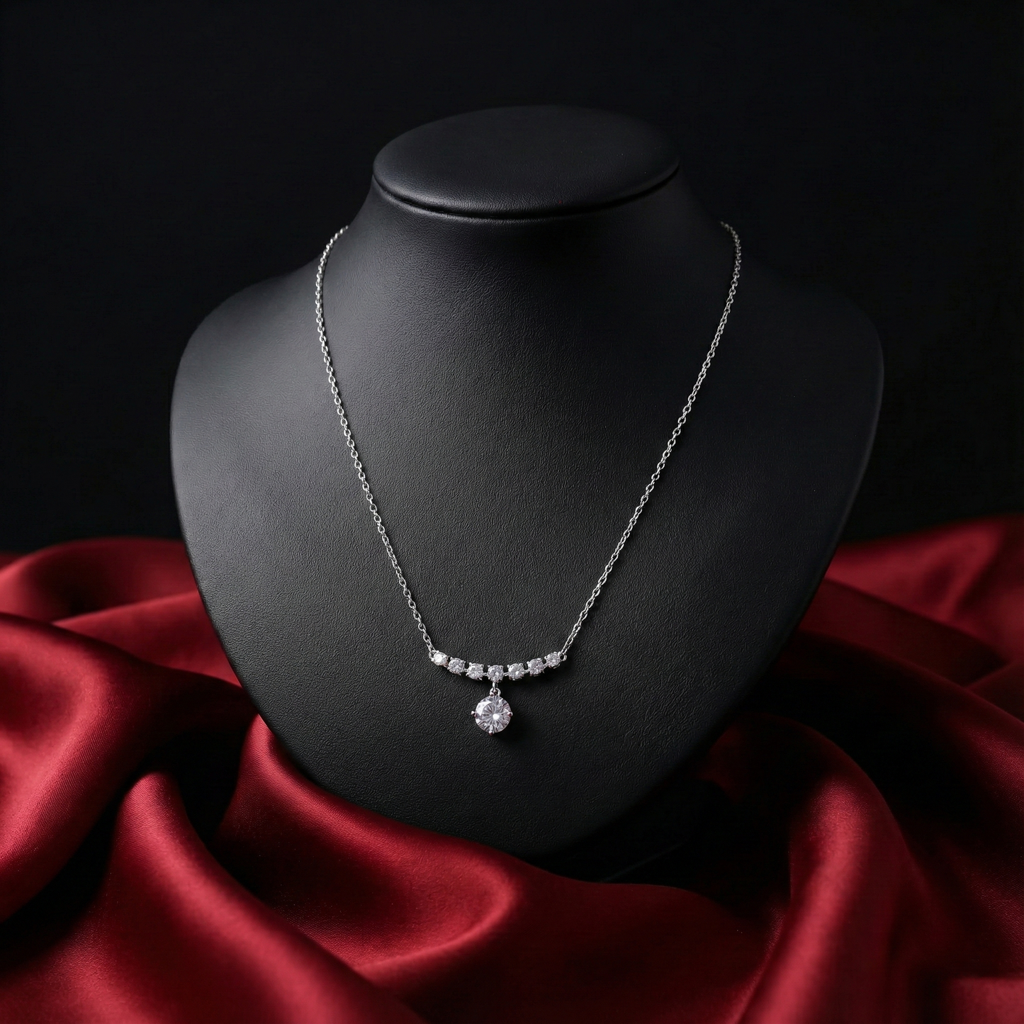 Silver necklace on a black mannequin bust with red fabric underneath