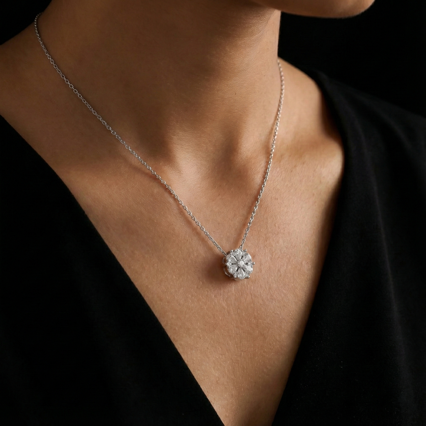 Silver necklace with a diamond pendant on a person wearing a black top.