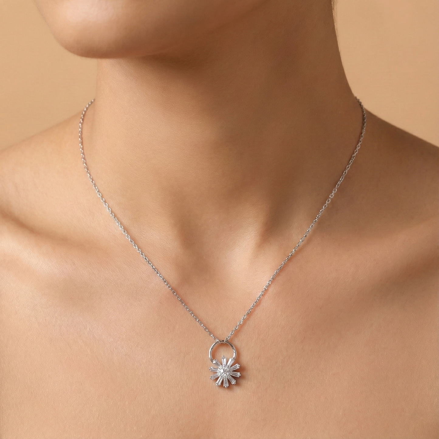 Silver necklace with a flower pendant on a person against a beige background