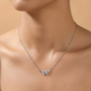 Silver necklace with a leaf pendant on a person against a beige background