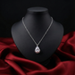 Silver necklace with a teardrop pendant on a black mannequin bust against a red fabric background