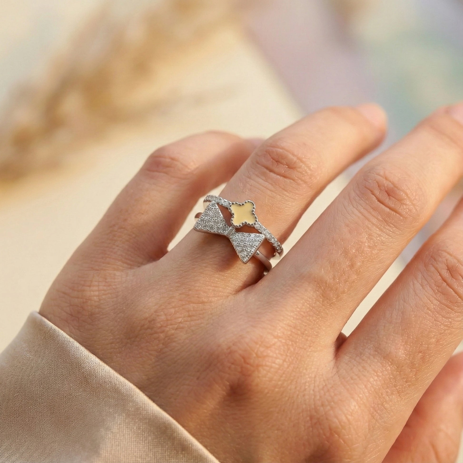 Silver ring with a heart design on a person's finger against a blurred background