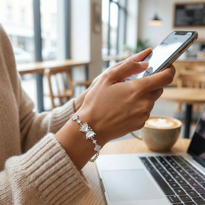 Person using a smartphone in a cafe setting with a laptop and coffee cup on the table.
