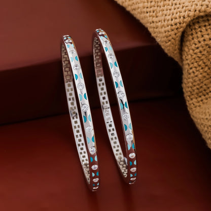 Pair of silver bangles with turquoise stones on a brown background