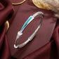Silver bracelet with blue accent on a burgundy fabric background