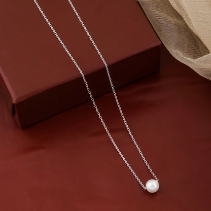 Pearl necklace on a red surface with a brown box in the background