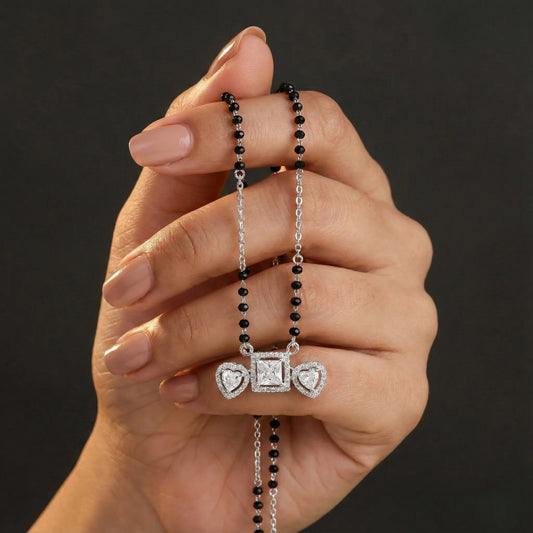 Hand holding a necklace with a pendant against a dark background