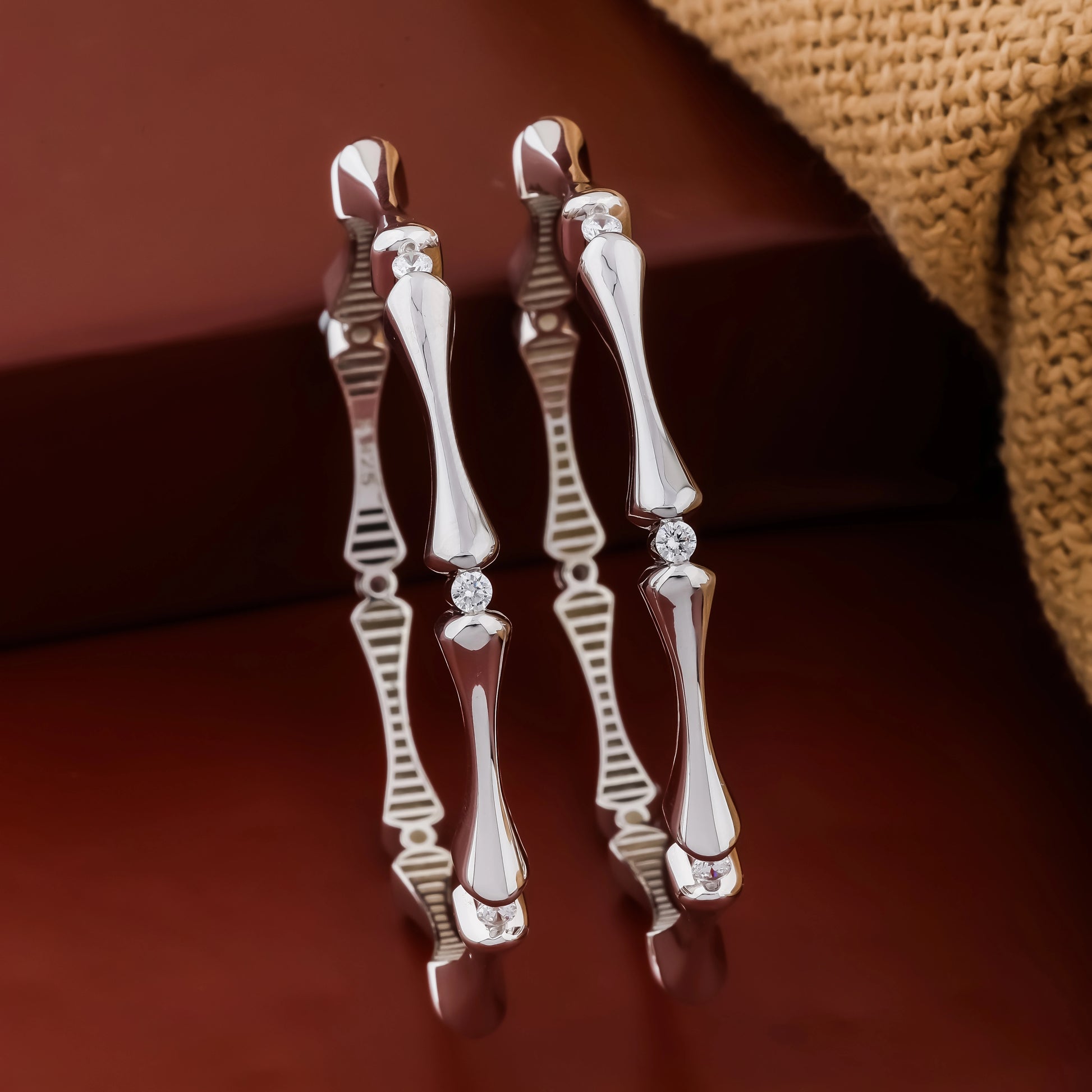 Pair of silver earrings with diamond accents on a brown background
