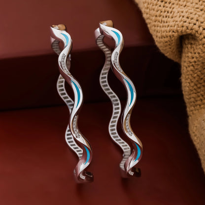 Pair of silver earrings with blue accents on a brown background