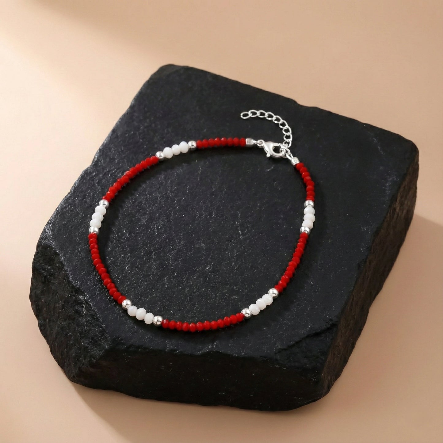 Necklace with red and white beads on a dark stone surface