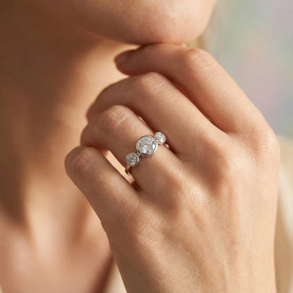 Close-up of a hand wearing a diamond ring with a blurred background