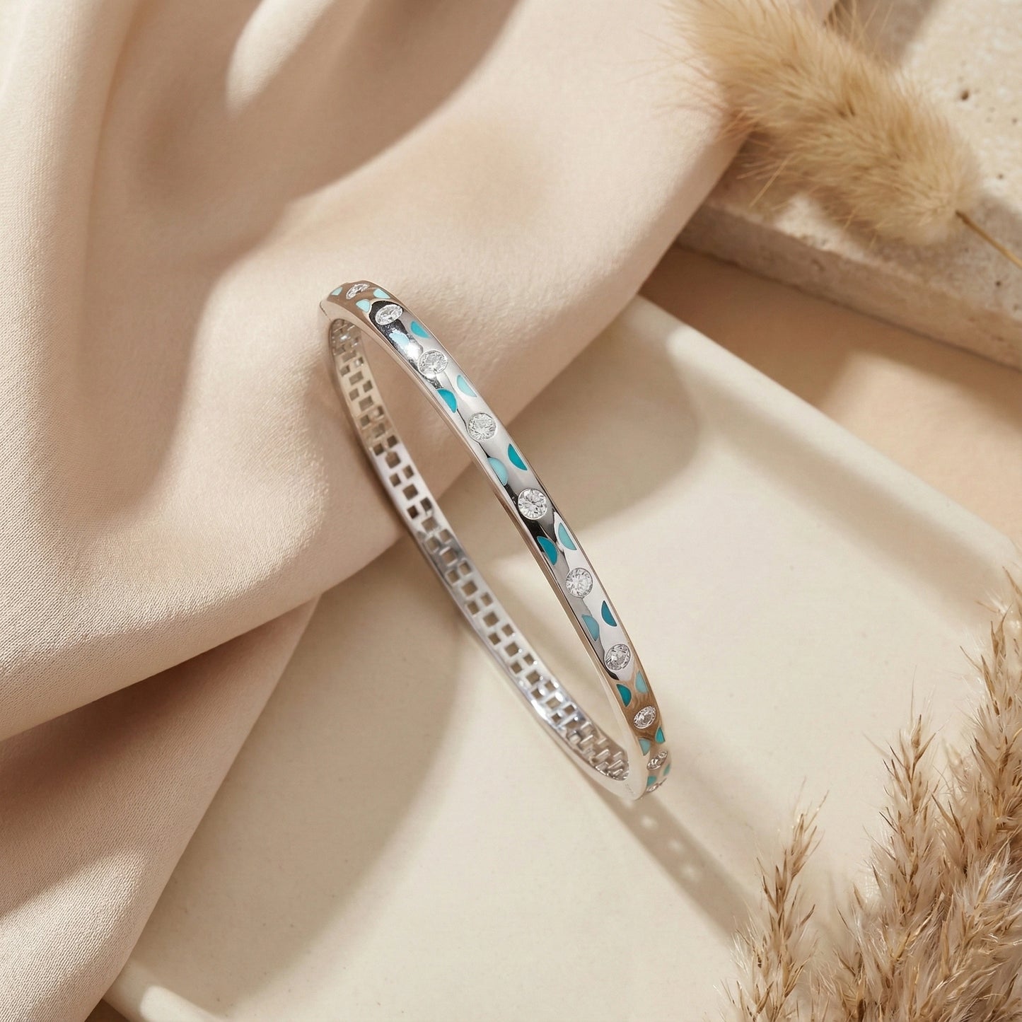 Silver bracelet with blue accents on a soft beige fabric background