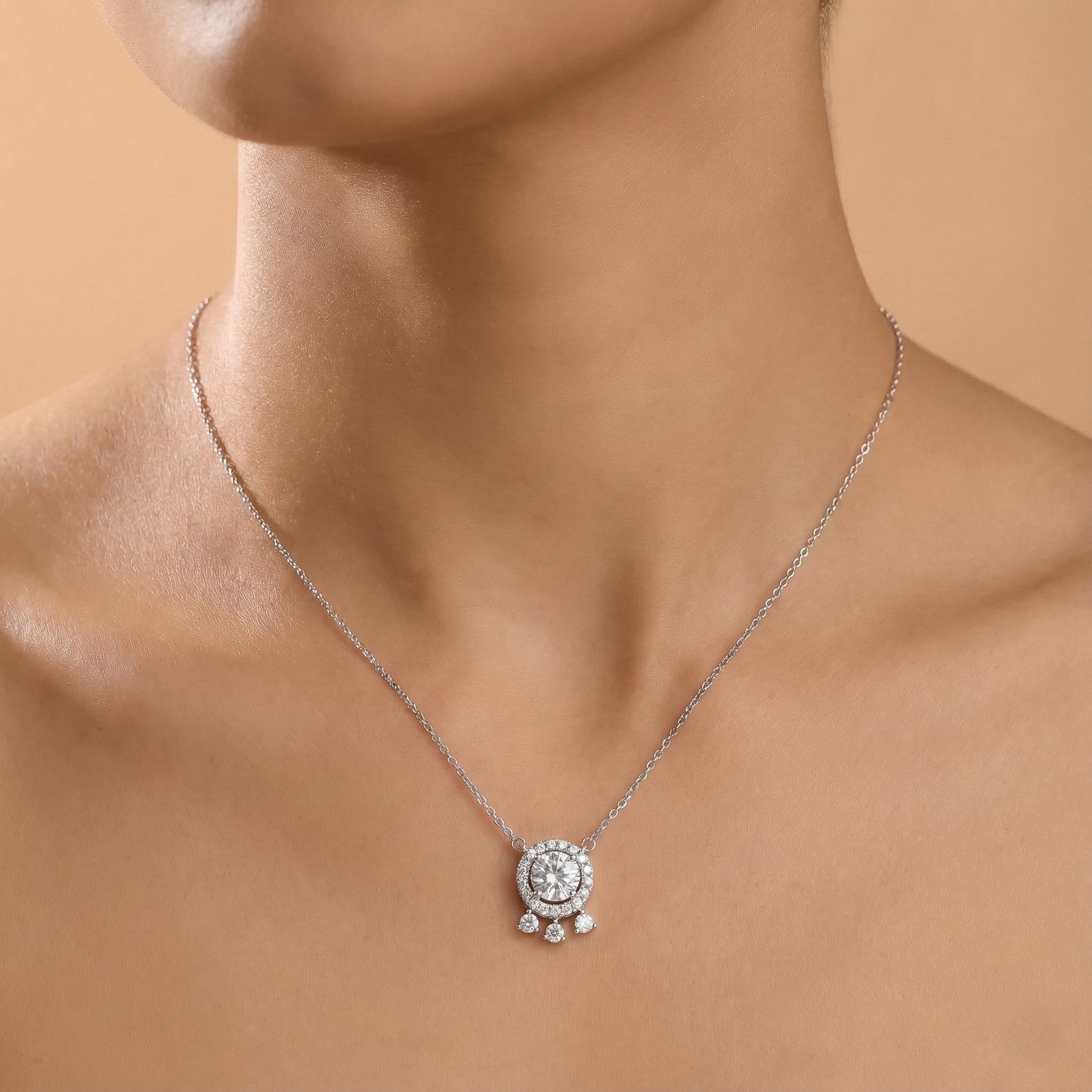 Silver necklace with a pendant on a model against a beige background