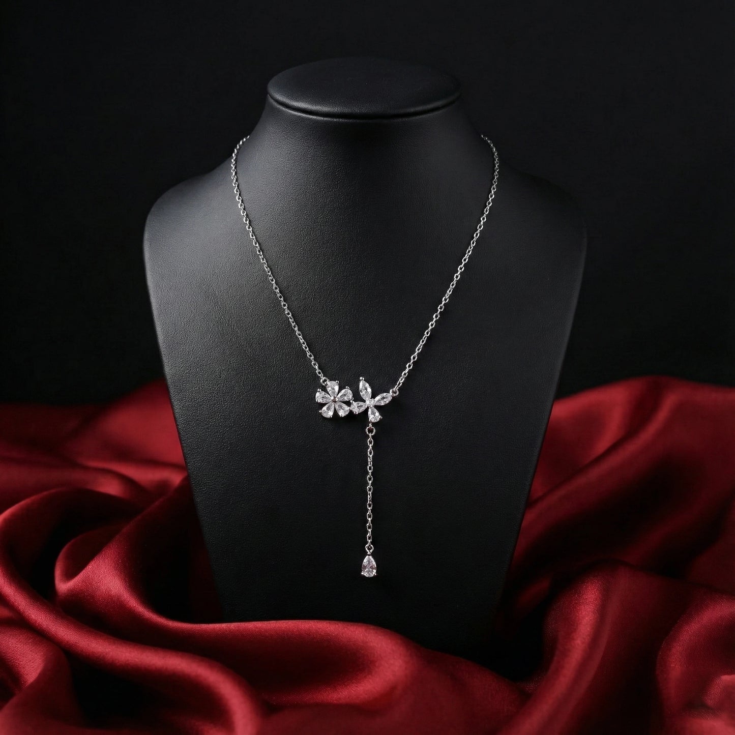 Silver necklace with floral design on a black mannequin against a red fabric background
