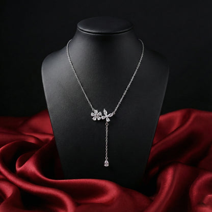 Silver necklace with floral design on a black mannequin against a red fabric background