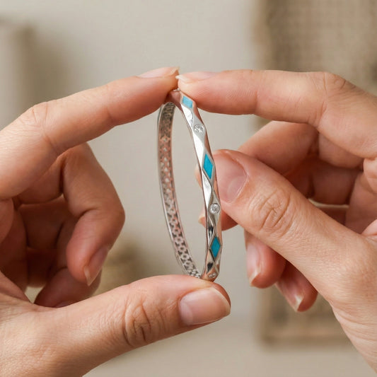 Close-up of hands holding a silver bracelet with blue accents.
