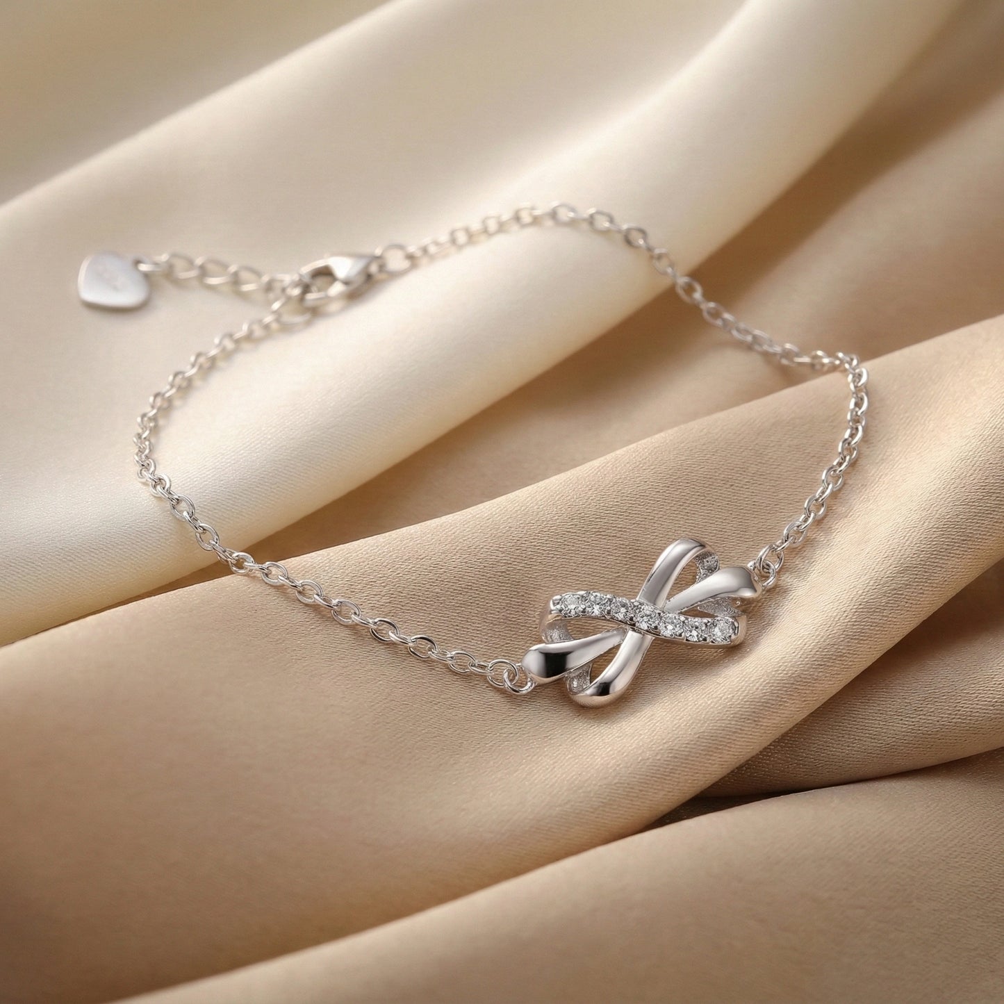 Silver bracelet with a bow design on a beige fabric background