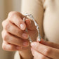 Close-up of hands holding a silver bracelet against a blurred background