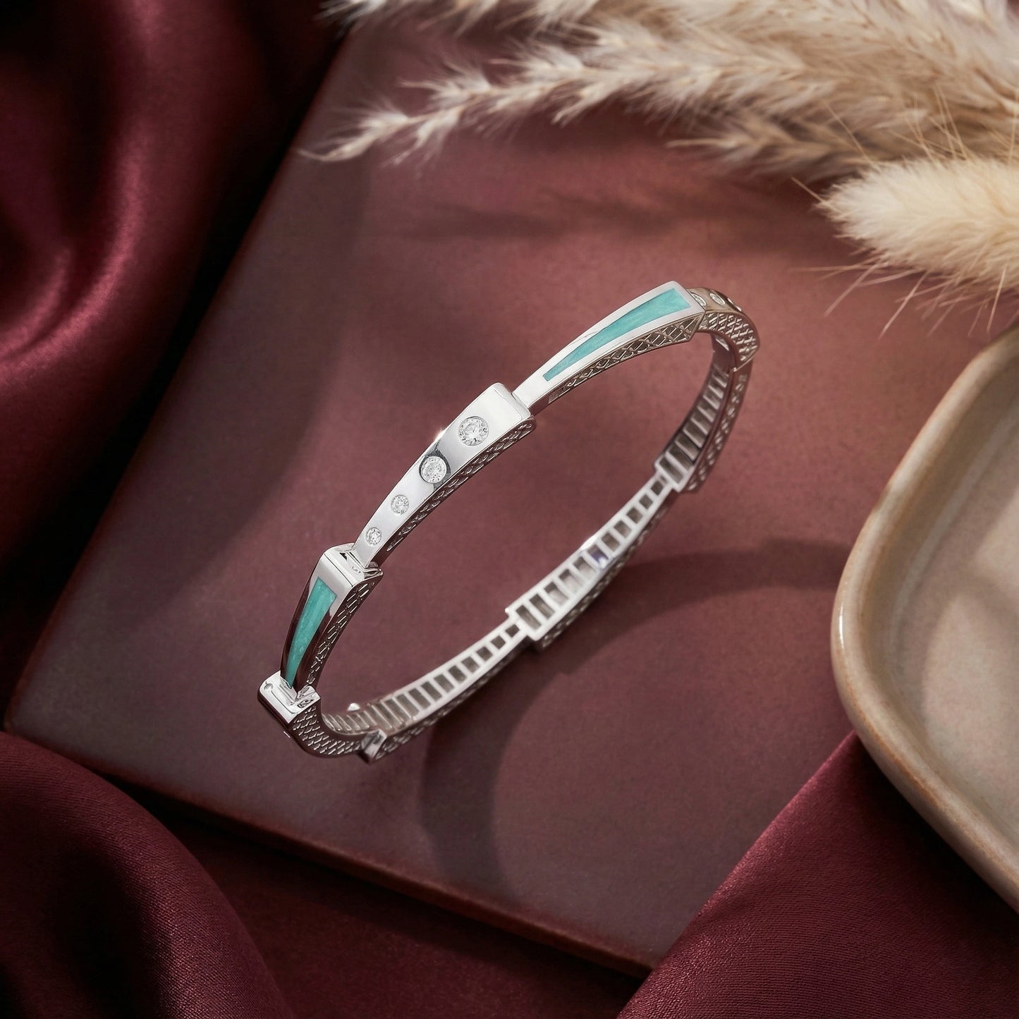 Silver bracelet with turquoise accents on a maroon surface with fur and ceramic dish
