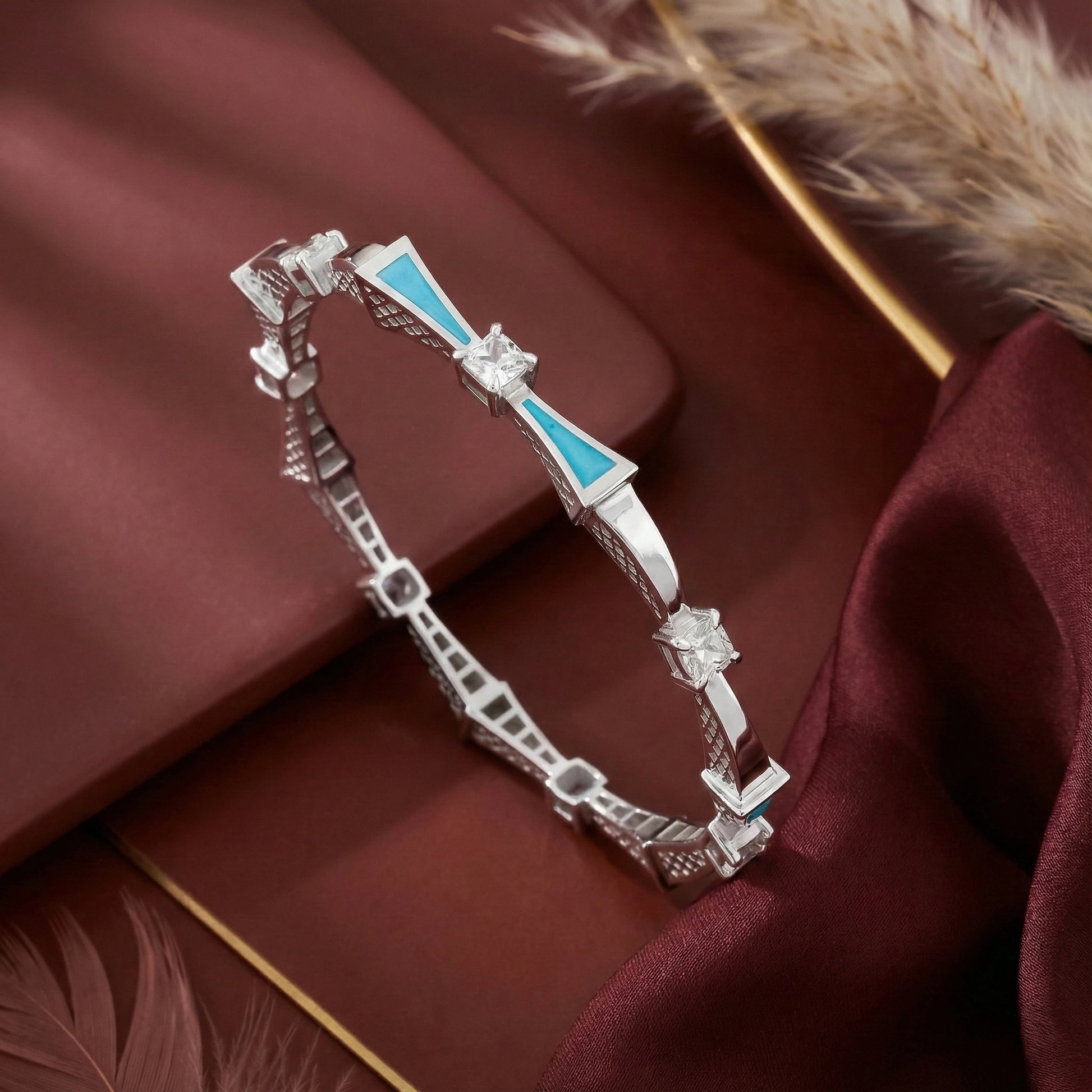 Silver bracelet with blue accents on a red fabric background