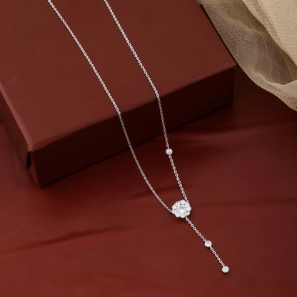 Silver necklace with a floral pendant on a brown surface