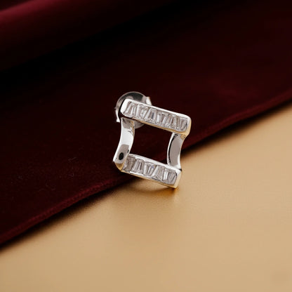 Silver earring with 'HUGUET' branding on a dark red fabric background