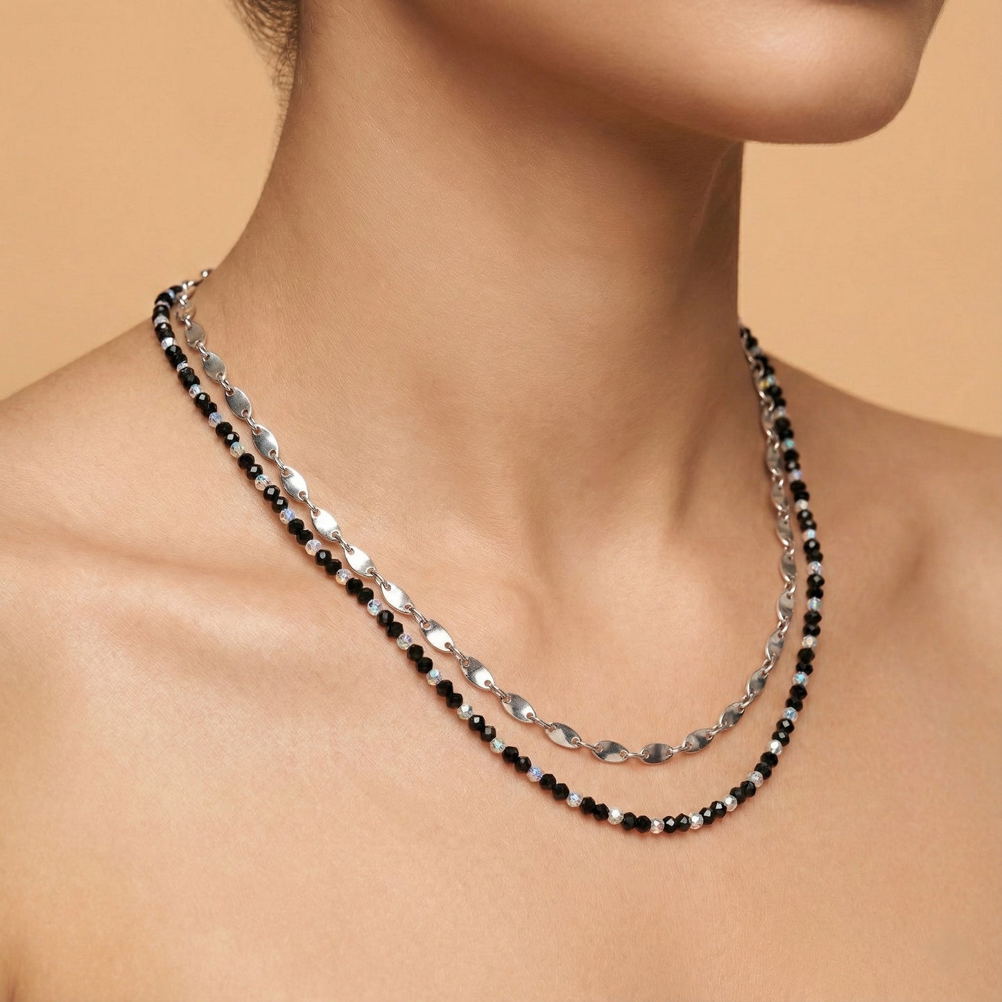 Necklace with black and silver beads on a person against a beige background