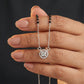 Hand holding a silver necklace with a round pendant against a dark background