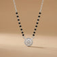 Necklace with black beads and a silver pendant on a beige background