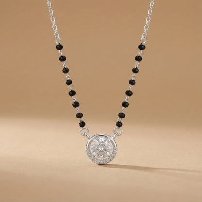 Necklace with black beads and a silver pendant on a beige background