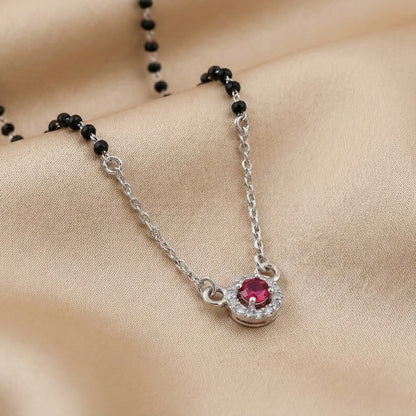 Silver necklace with a red gemstone pendant on a beige fabric background