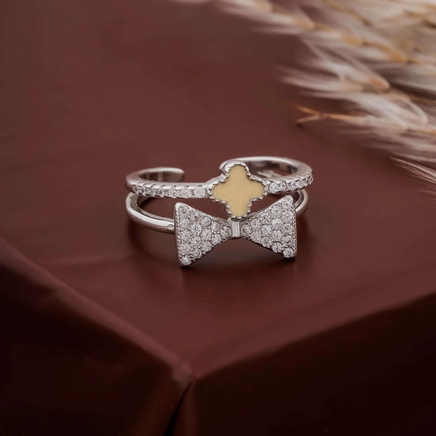 Silver bow-shaped ring with a gold center on a brown surface