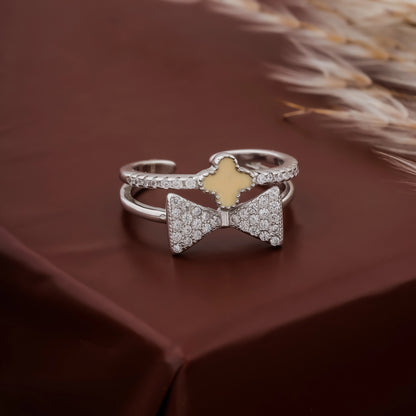Silver bow-shaped ring with a gold center on a brown surface