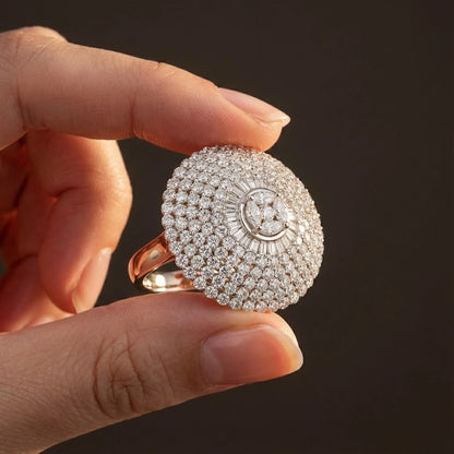 Hand holding a diamond-encrusted ring against a dark background
