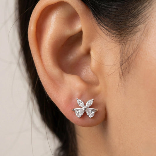 Butterfly-shaped earrings worn on an ear with a neutral background
