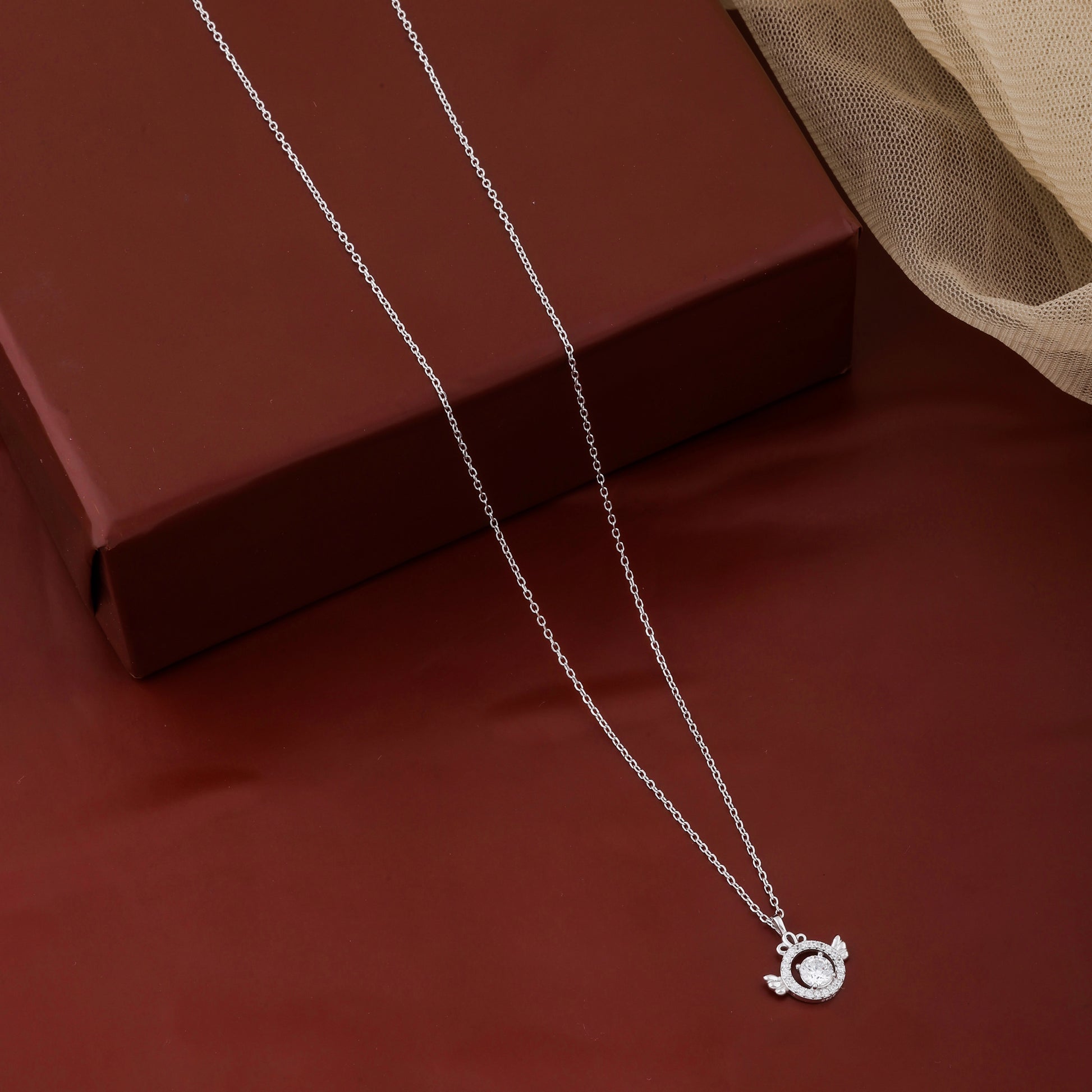 Silver necklace with a pendant on a red surface