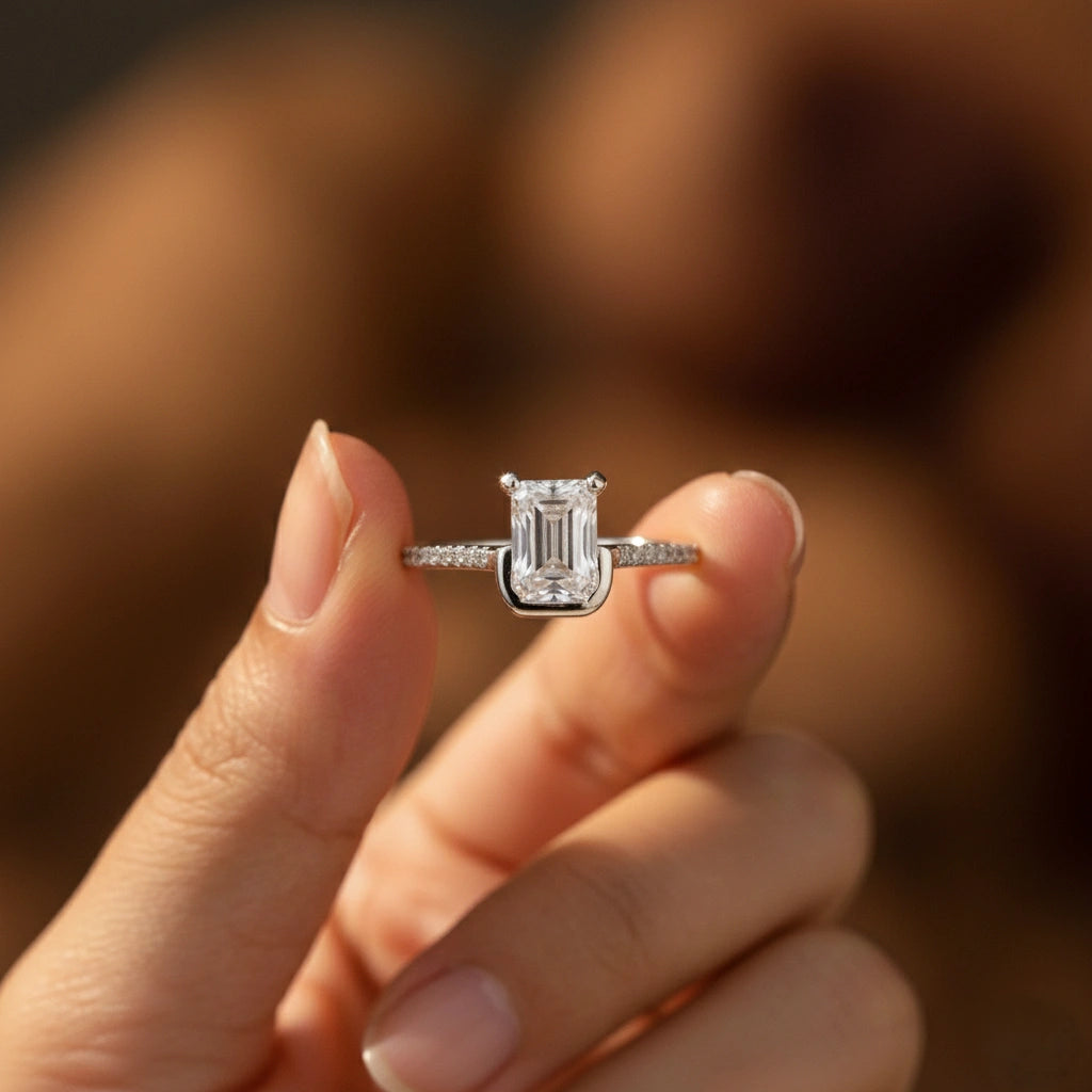 Diamond ring held between two fingers with a blurred background