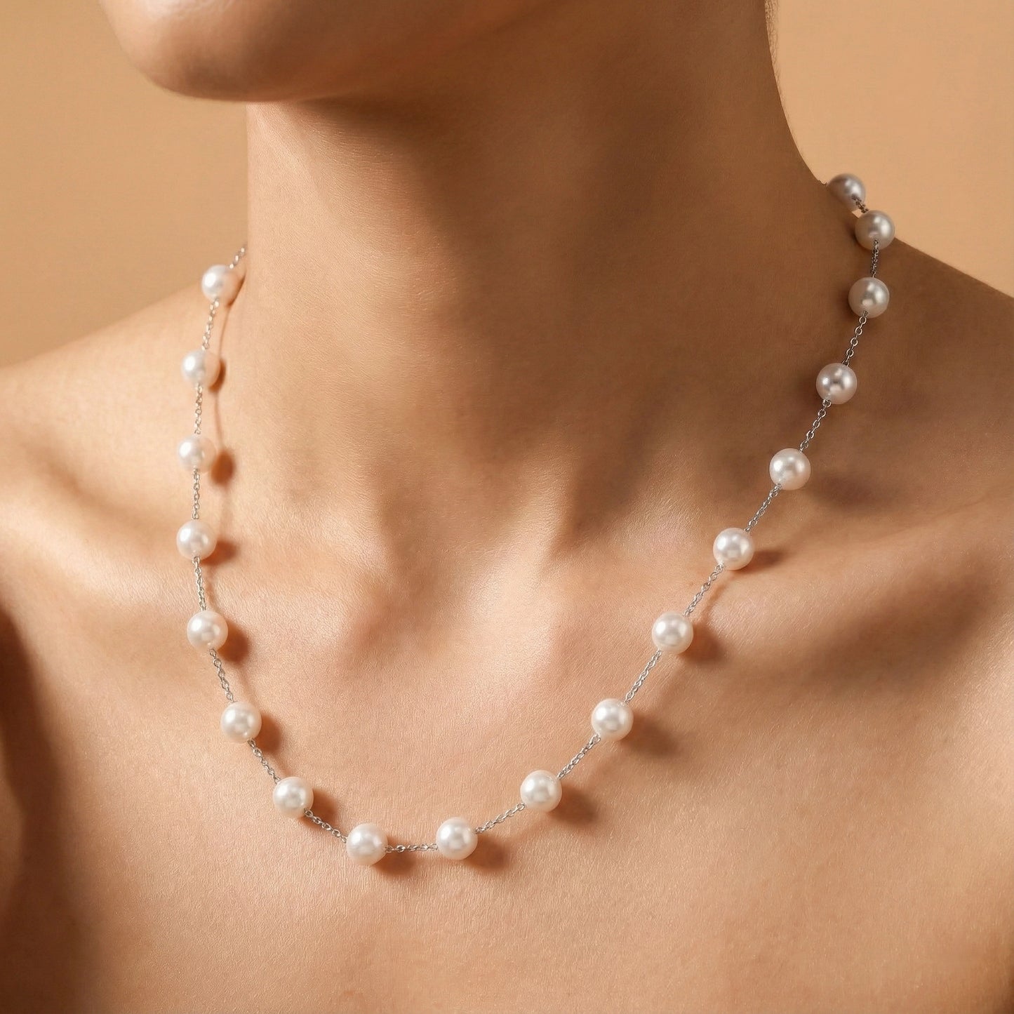 Pearl necklace on a person against a beige background
