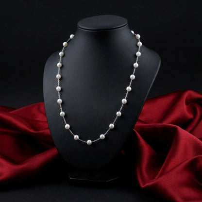 Pearl necklace on a black mannequin bust with red fabric in the background