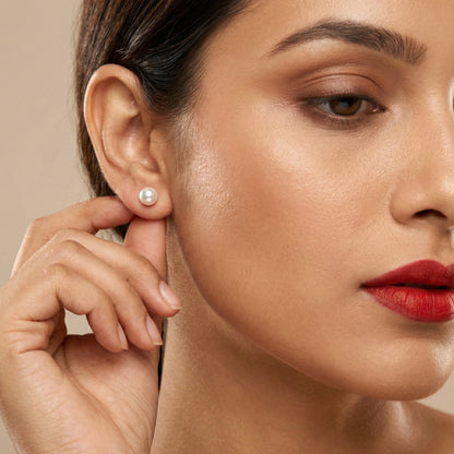 Close-up of a woman wearing a pearl earring against a neutral background