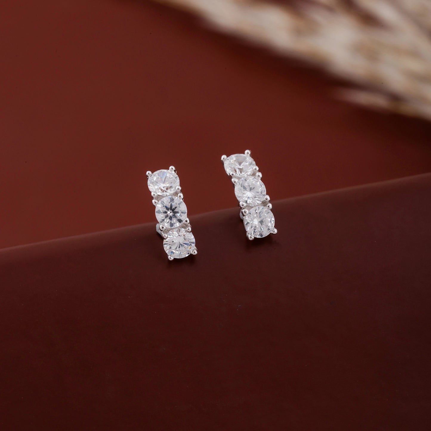 Pair of diamond stud earrings on a brown surface