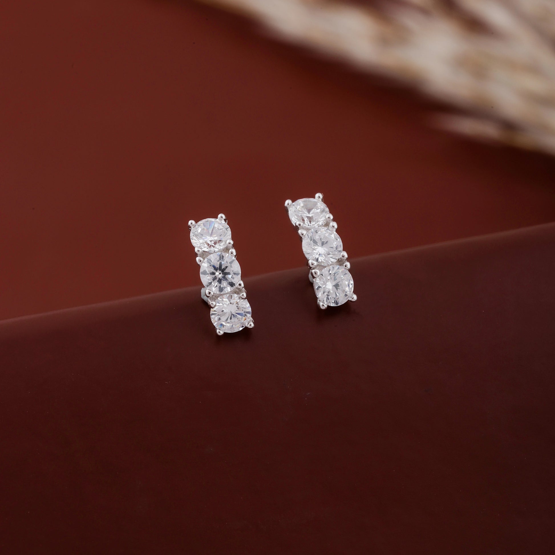 Pair of diamond stud earrings on a brown surface
