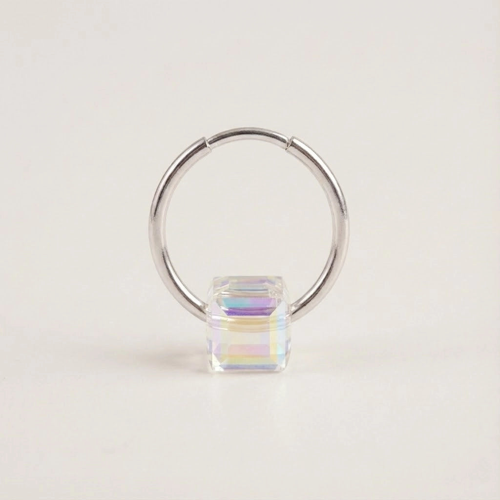 Silver hoop earring with a colorful square gemstone on a light beige background