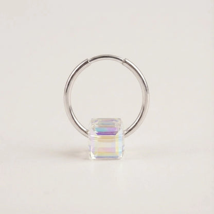 Silver hoop earring with a colorful square gemstone on a light beige background