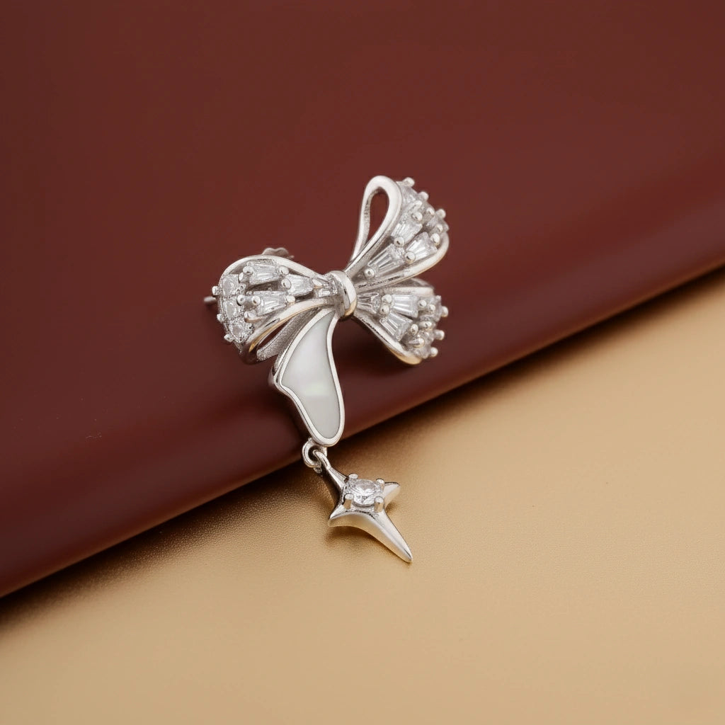 Silver bow-shaped earring with a star detail on a brown background