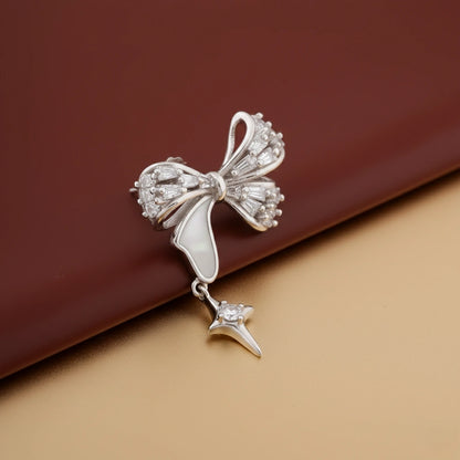 Silver bow-shaped earring with a star detail on a brown background