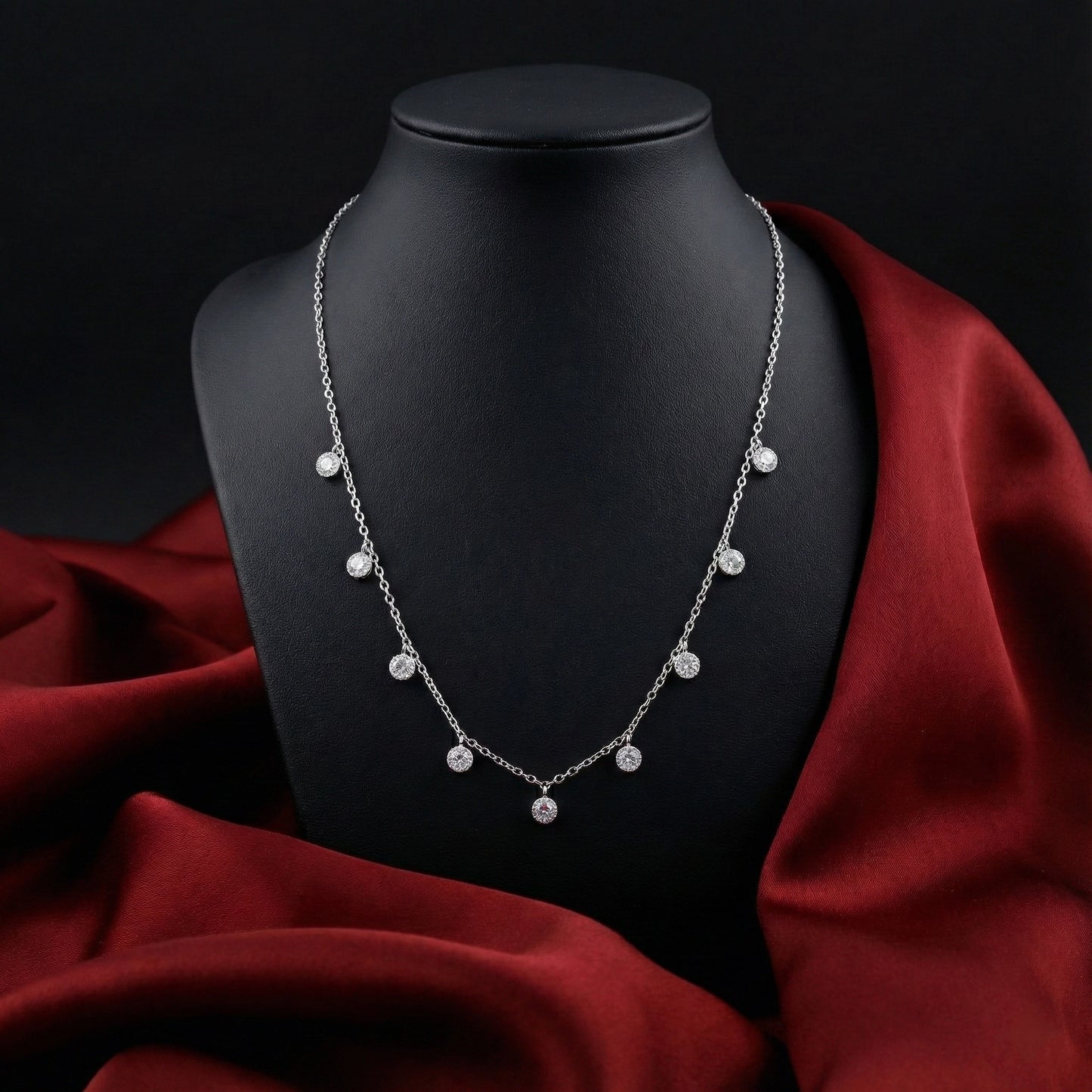 Silver necklace on a black mannequin with red fabric background