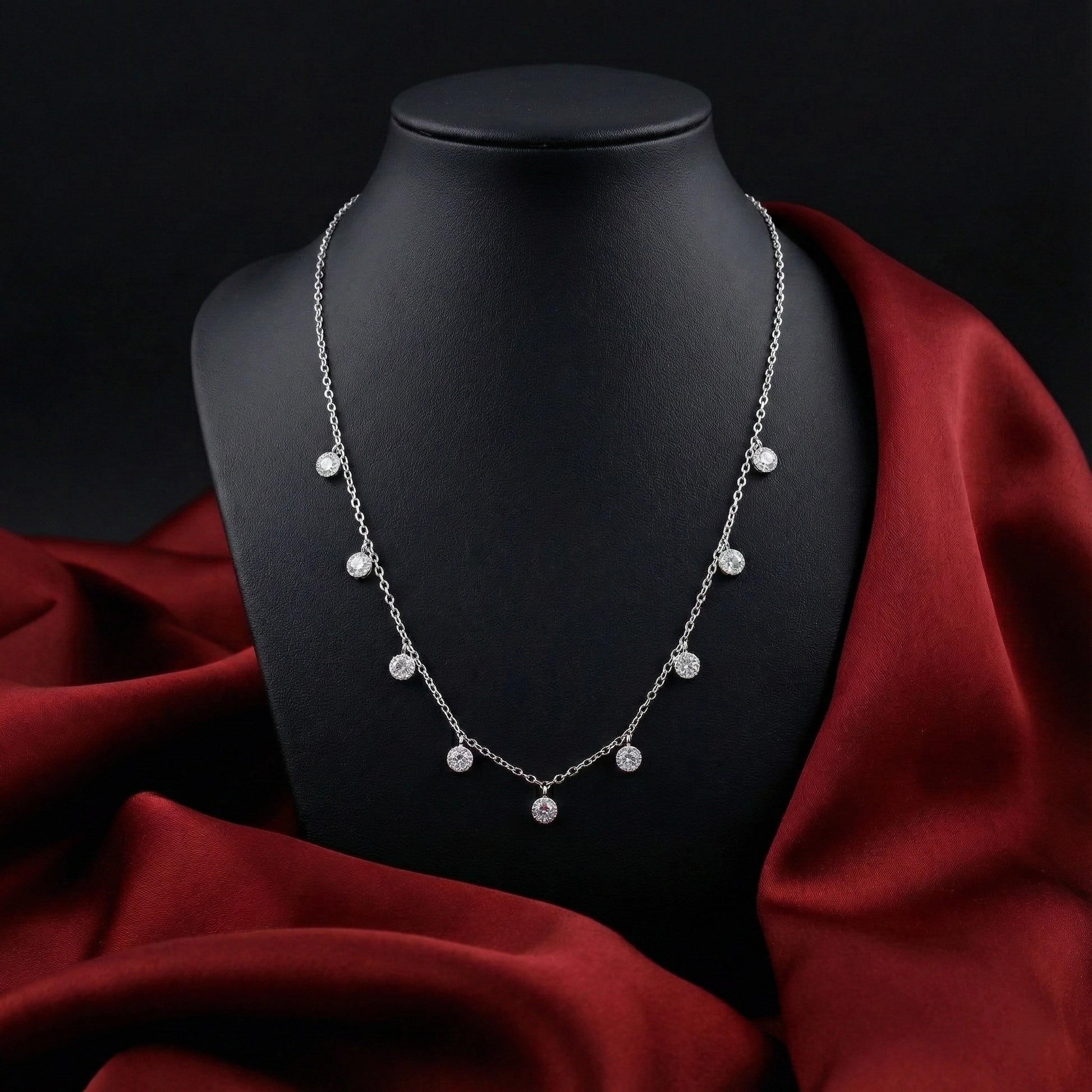 Silver necklace on a black mannequin with red fabric background
