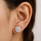 Close-up of an ear wearing a round diamond stud earring.